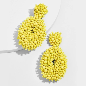 Detailed view of yellow beaded drop earrings on a white minimalist display stand