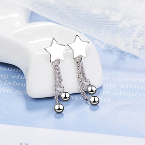 Elegant silver star tassel earrings with long chain and ball pendants on a display stand