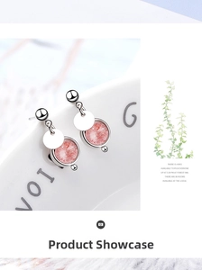 Close-up of pink strawberry quartz drop earrings hanging on a ceramic dish edge