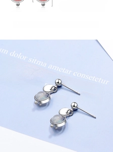 Macro detail of silver stud earrings featuring round strawberry quartz stone pendant