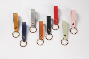 Close-up of colorful leather keychains with rose gold rings and metal rivets in eight colors