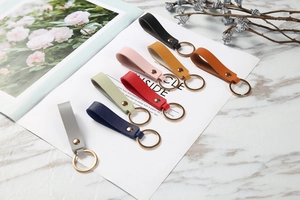Close-up of leather keychains in eight colors with golden rings and metal rivets