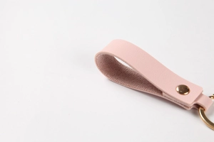 Macro shot of pink litchi grain leather keychain with gold rivet and metallic ring