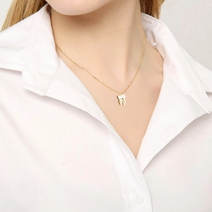 Collier avec pendentif en forme de dent dorée sur chaîne en acier inoxydable