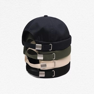 Gros plan de bonnets docker en coton empilés en noir, vert armée et beige avec boucles métal