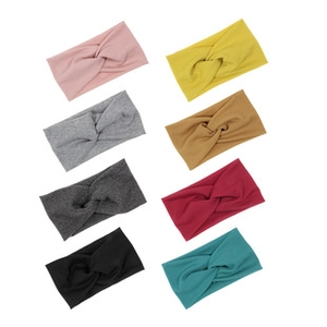 Flat lay of eight colorful knitted twist headbands for girls in various pastel shades