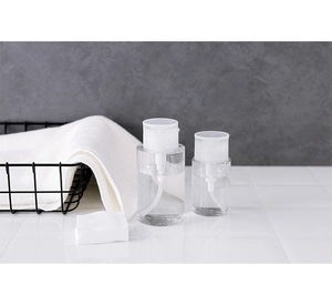 Close-up of clear refillable pump bottles for makeup remover on a bathroom counter
