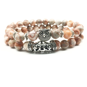 Macro detail of natural agate beads with silver owl charm and engraved metal tube