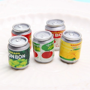 Miniature juice can charms for DIY jewelry and keychains on a white ceramic plate