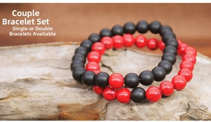 Detail view of 8mm black and red natural stone beaded bracelets on a rustic wood surface
