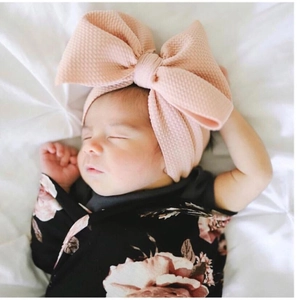 Pink waffle fabric oversized bow headband for babies worn by an infant model