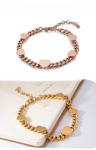 Primo piano di bracciali in acciaio inossidabile con ciondoli a cuore in oro e rosa