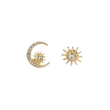 Vue détaillée des boucles d'oreilles asymétriques dorées avec lune, soleil et cristaux