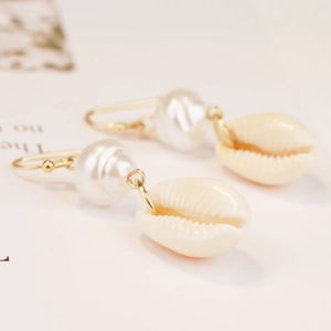 Detailed shot of bohemian shell earrings with gold metal hooks and white pearls