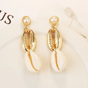 Detailed shot of bohemian gold earrings with round pearls and natural white sea shells