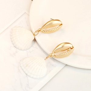 Detail of seashell drop earrings with gold metal stud on elegant marble surface