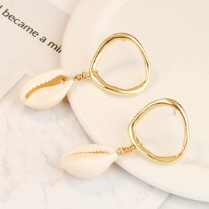 Detailed close-up of Bohemian gold hoop earrings with natural white cowrie shell pendants