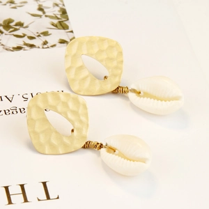 Detail of bohemian pearl shell earrings with hammered gold metal on a magazine page