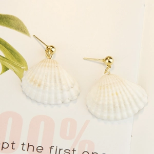 Close-up of bohemian shell earrings with natural white texture and gold metal studs