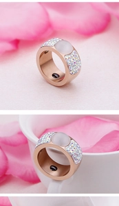 Close-up of rose gold ring with white opal and colorful crystals on pink petals