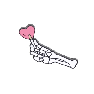 Detailed view of punk skeleton hand enamel pin holding a pink heart lollipop
