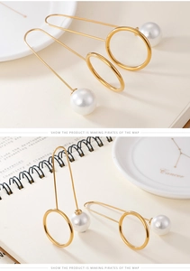 Detailed view of long gold geometric drop earrings with elegant white pearl accents