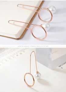 Detail view of rose gold drop earrings with pearl charm and geometric hollow ring design
