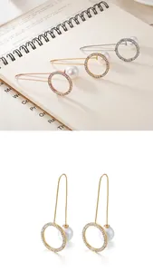 Detail view of long geometric earrings with shell pearls and cubic zirconia in three finishes