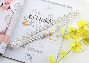 Detailed view of triple-row pearl waist chain with a delicate bow buckle decoration