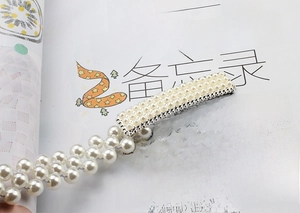 Detail of elegant triple-row pearl hair clip on a magazine showing classic vintage style