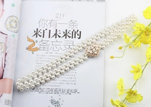 Detail of elegant pearl waist chain featuring a sparkling rhinestone heart buckle