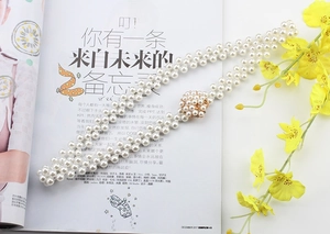 Detail of multi-layer faux pearl waist chain with gold rhinestone buckle on a magazine