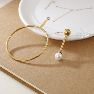 Elegant gold circle stud earring set with white pearl and bead on ceramic dish