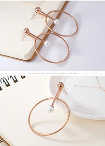 Detailed view of rose gold hoop earrings with white faux pearls on a minimalist background