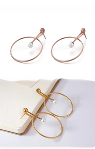 Detail of round pearl drop earrings in gold and rose gold on a minimalist background