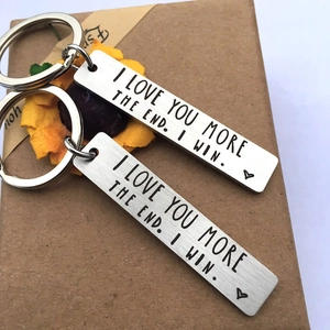 Detail of couple keychains engraved with I LOVE YOU MORE THE END on a gift box
