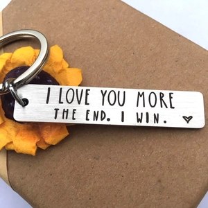 Close-up of engraved stainless steel bar keychain with I LOVE YOU MORE text in gift box