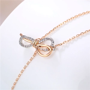 Two-tone bowknot necklace with crystals on gold chain shown on white background