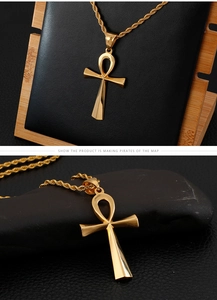 Detail showing gold Ankh cross pendant on twisted chain over black stone and leather base