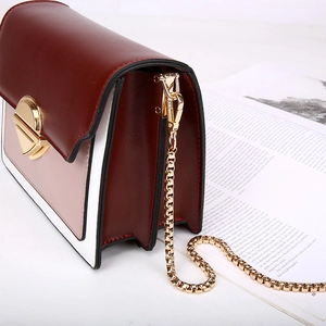 Chic burgundy and white colorblock handbag with a gold chain strap on a magazine