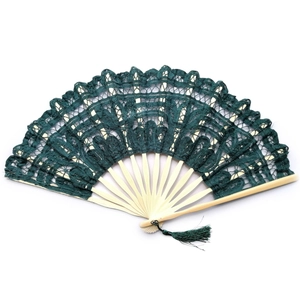 Detail of dark green lace fabric and bamboo ribs on a vintage folding fan with tassel