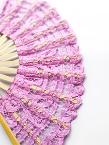 Detailed view of pink lace fabric pattern on a traditional vintage bamboo folding fan