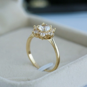 Détail macro d'une bague flocon de neige dorée en zircon sur écrin en velours beige