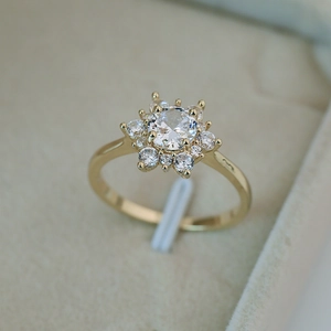 Bague flocon de neige dorée en zircon avec pierre centrale ronde dans un écrin beige