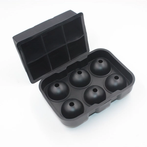 Detail view of a black 6-cavity silicone spherical ice mold set on a white background