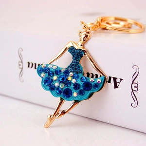 Golden alloy ballet girl keychain with blue crystals on white vintage book background