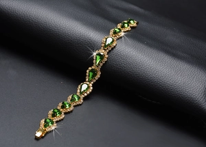 Vue macro d'un bracelet doré avec cristaux verts en forme de goutte sur cuir noir