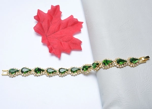 Gros plan détaillé d'un bracelet doré orné de pierres émeraude en poire et de strass brillants