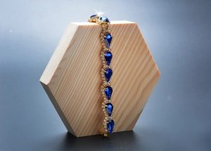Détail d'un bracelet doré avec gemmes gouttes bleues et cristaux étincelants
