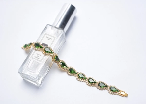 Détail du bracelet doré avec cristaux verts en goutte et petits diamants étincelants